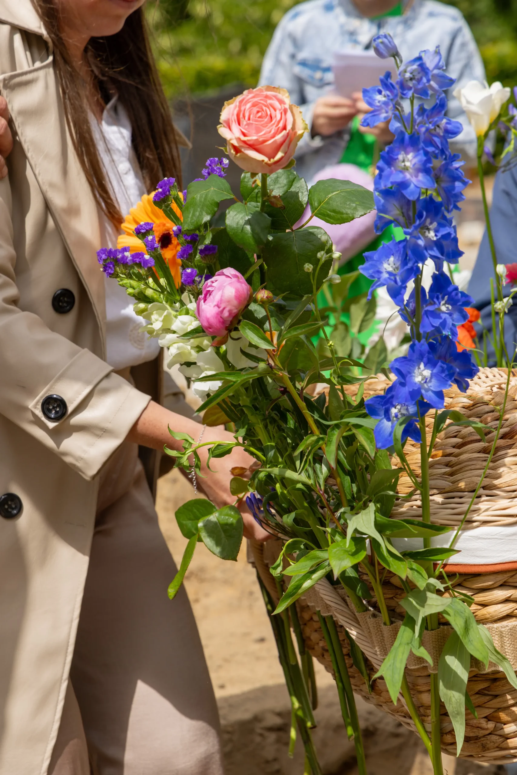 Afscheidsfotografie: moeder draagt een mandje met haar stil geboren kindje, omgeven door bloemen.